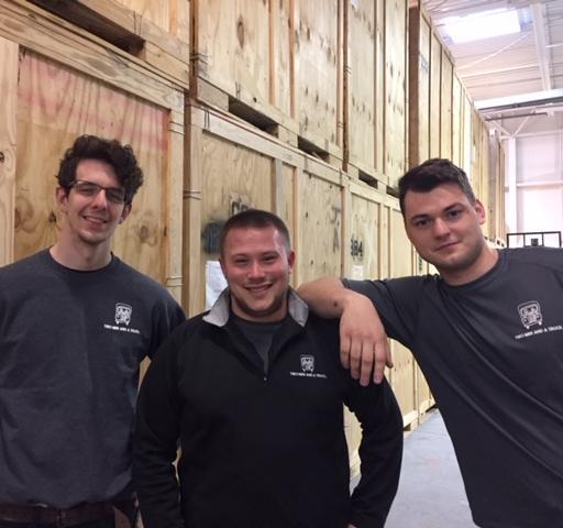 Three movers standing in front of storage crates