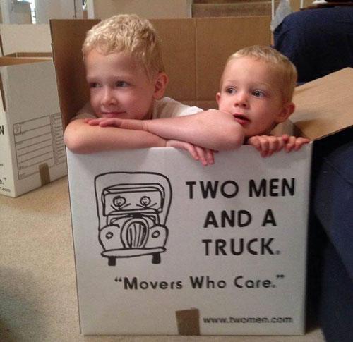 two kids sitting in a two men and a truck moving box