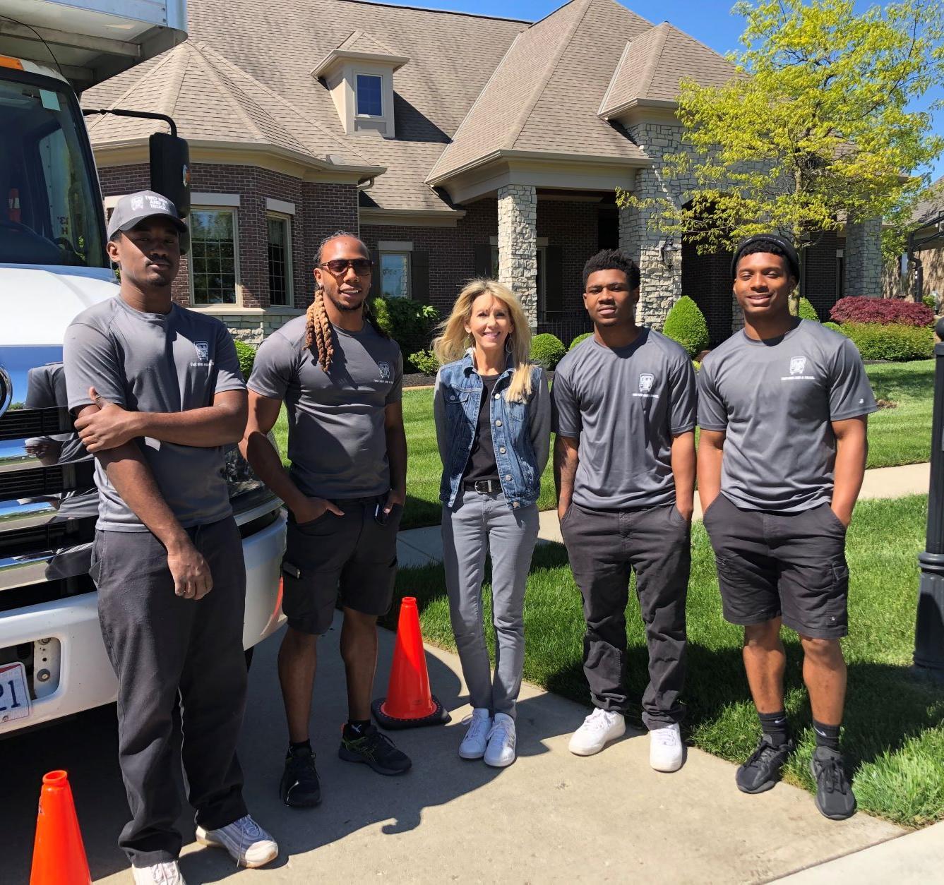 Four professional movers standing next to moving truck