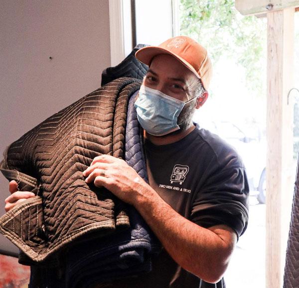 a mover carrying pads with a mask on