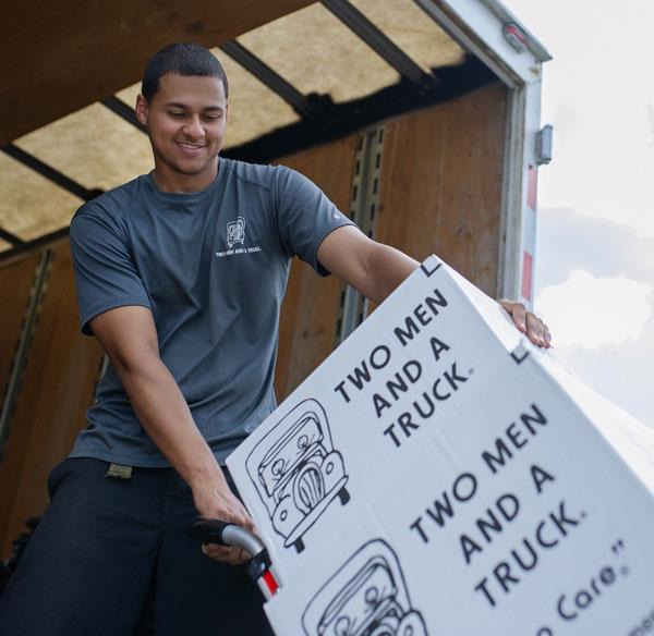 A mover loading boxes up a truck ramp