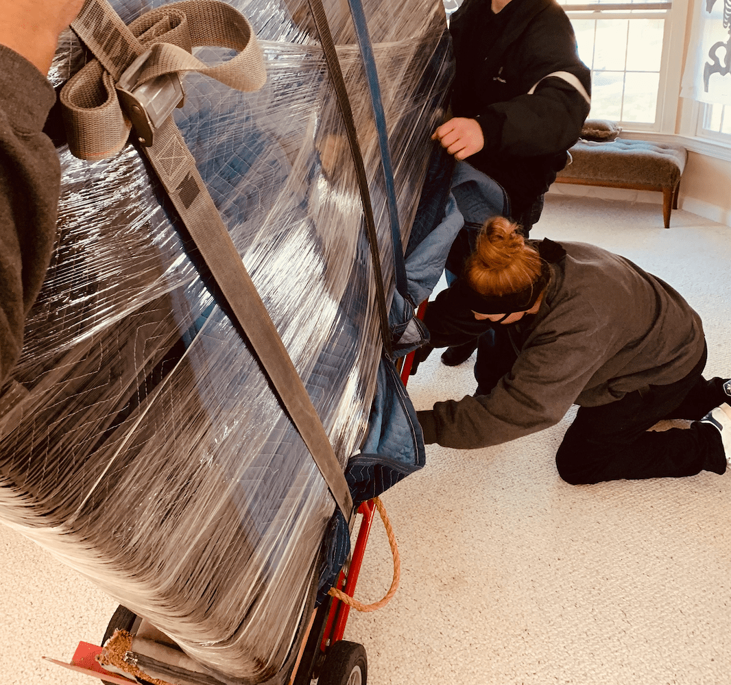 Mover strapping a piano to a piano board