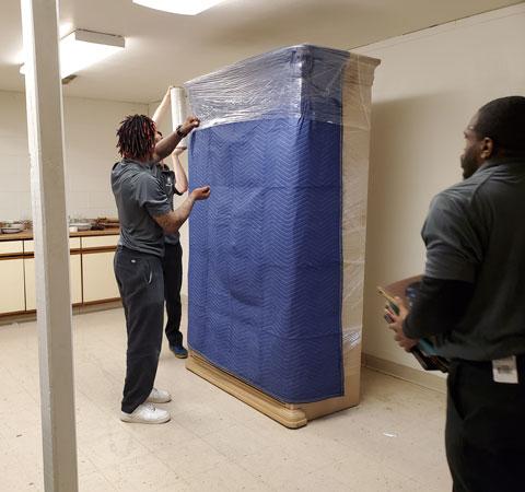 supervisor training a mover on wrapping a mattress