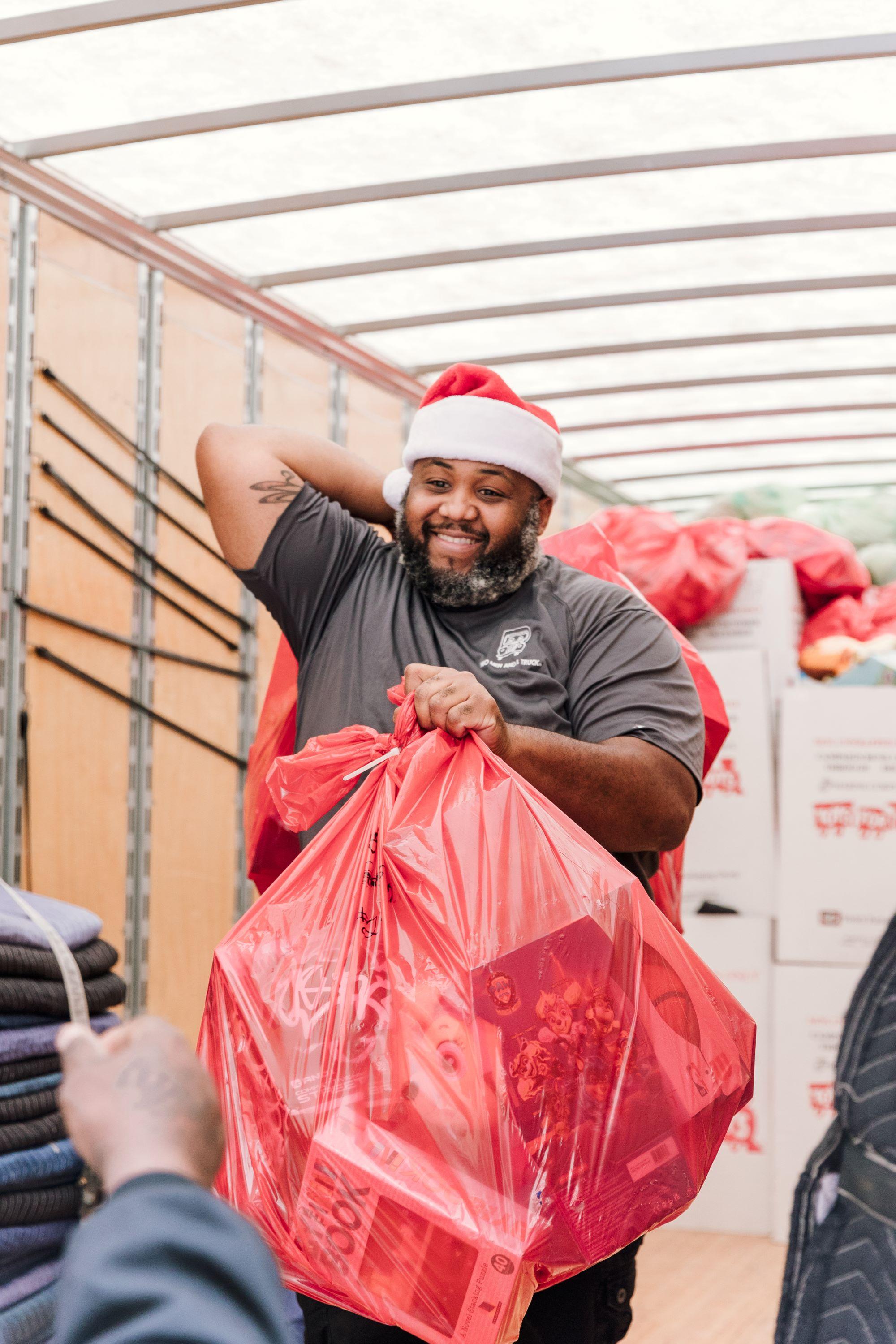 TWO MEN AND A TRUCK Dallas mover carrying bags filled with toys wearing a santa hat