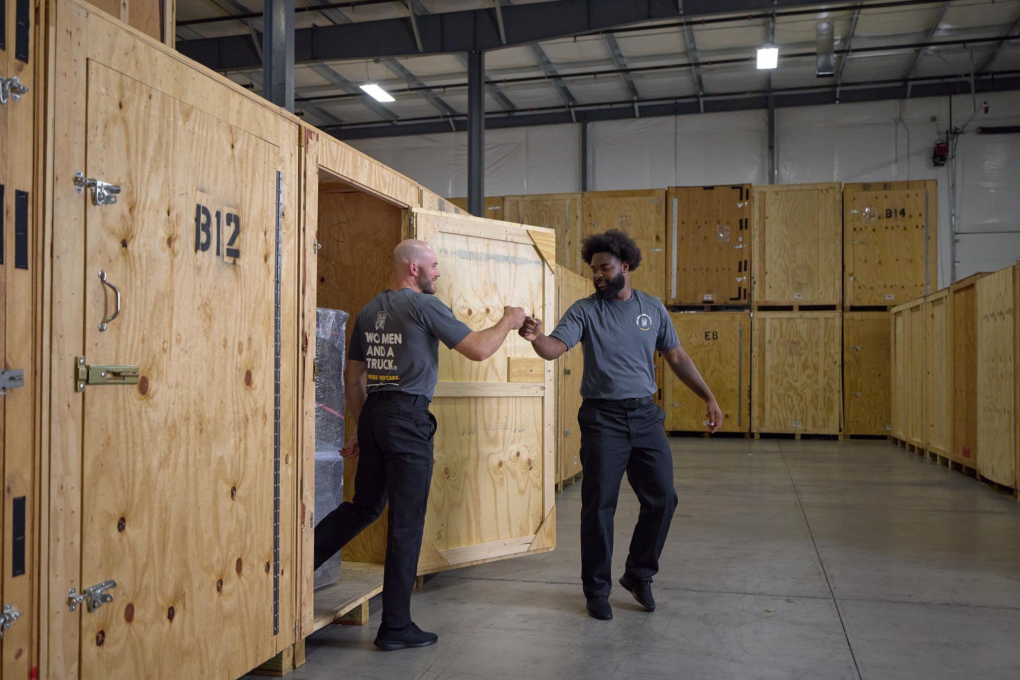 Two movers fist bumping in front of storage crates