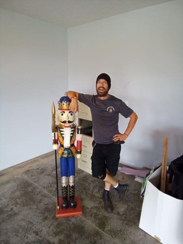 Mover smiling and standing next to Nutcracker statue