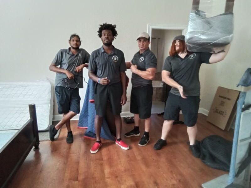 4 movers inside with one holding a wrapped chair