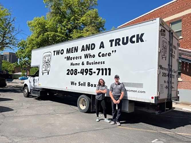 two movers standing in front of a truck