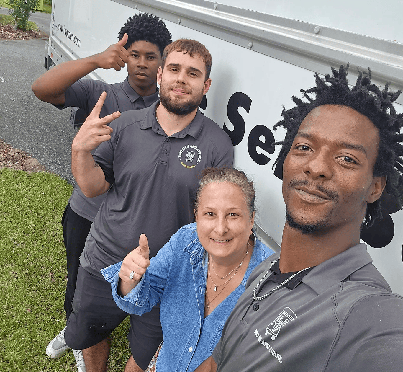 3 movers posing with a happy customer by a moving truck