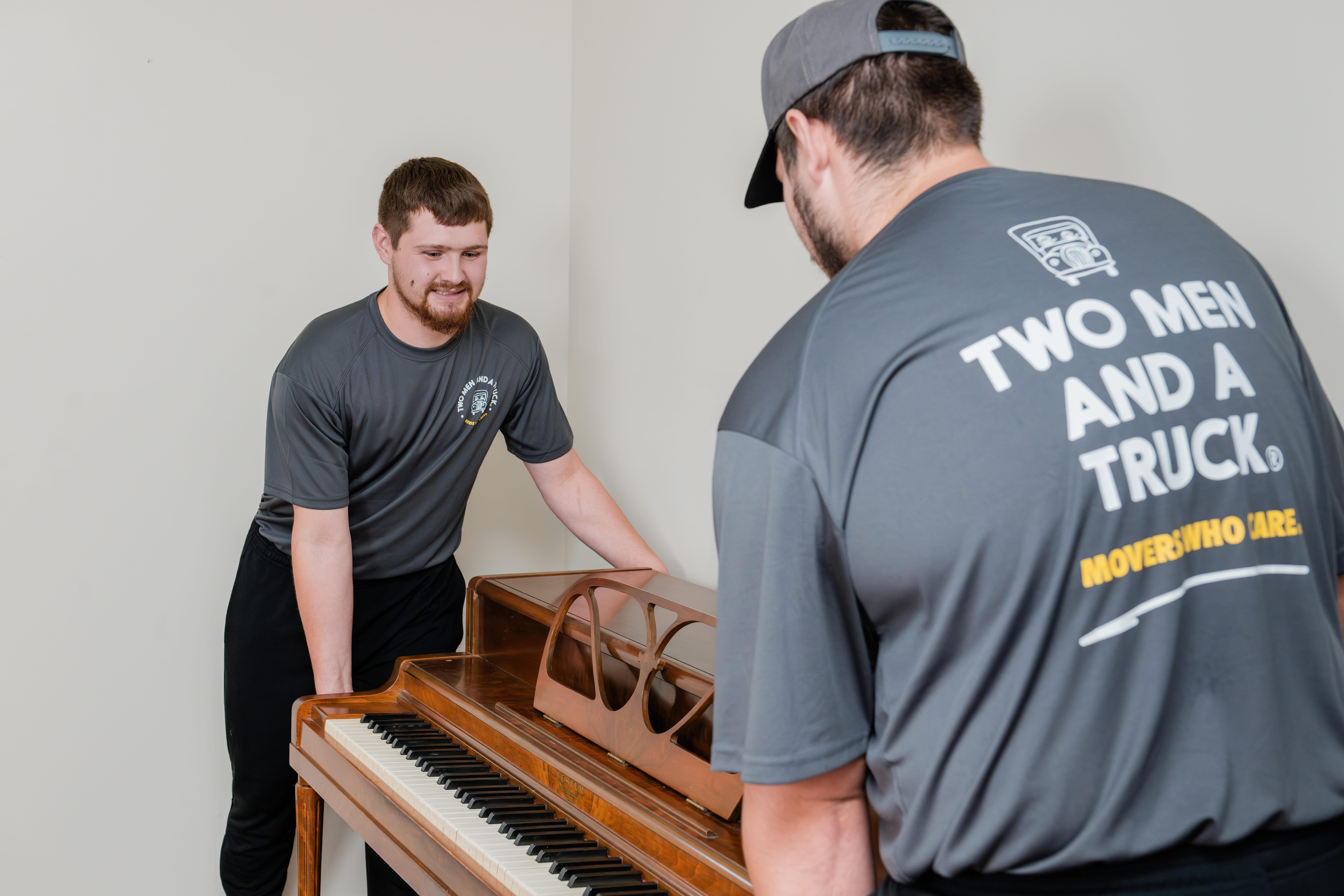 two movers grabbing an upright piano