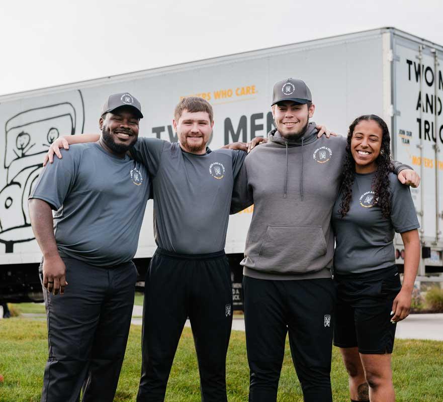 moving team huddled in front of truck smiling at the camera