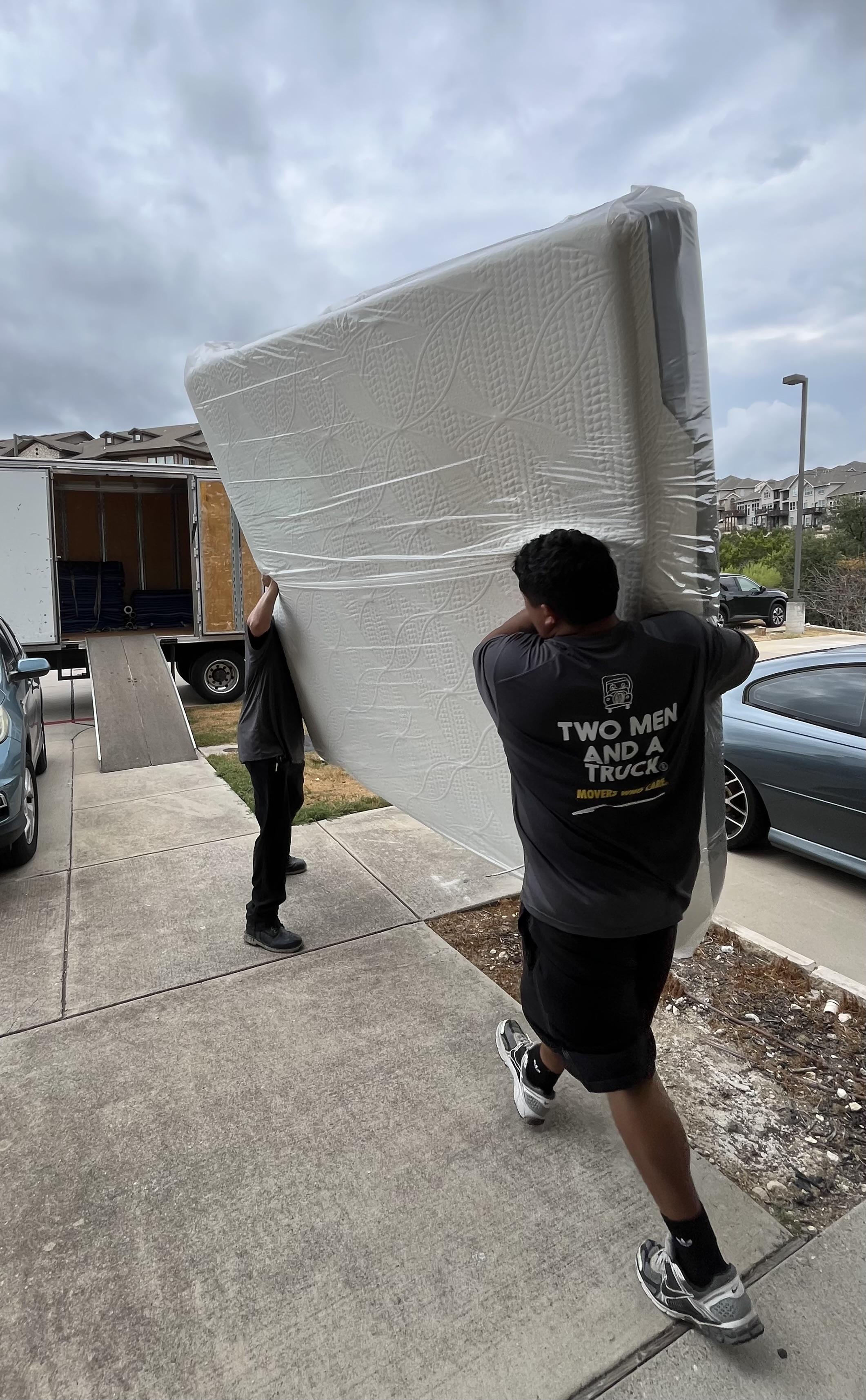 Movers carrying a mattress with mattress protection into a moving truck in Pflugerville TX