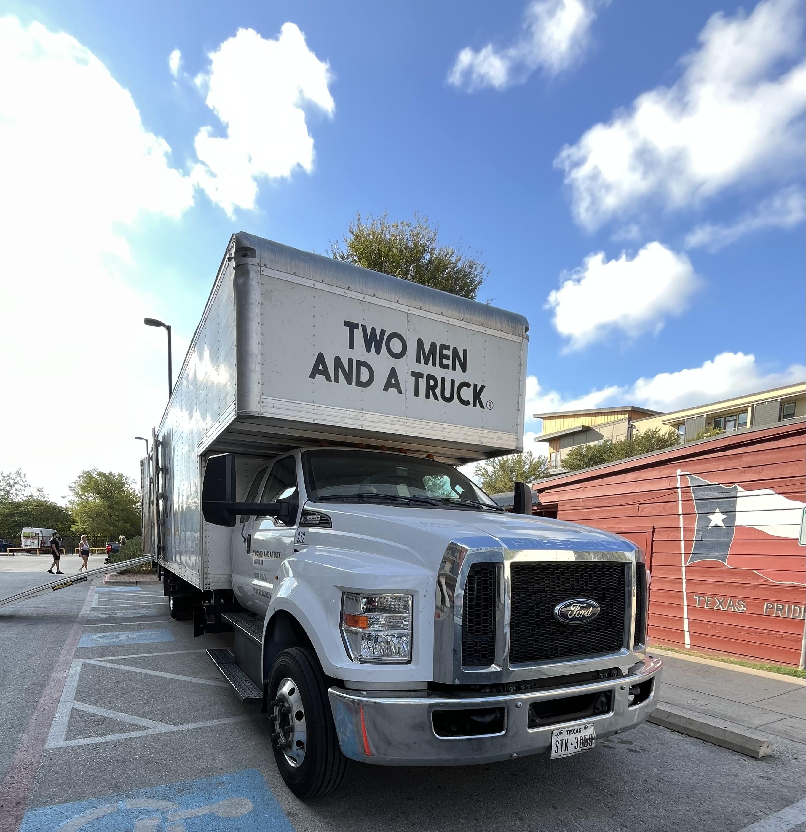 Two Men And A Truck truck parked in front of a storage unit with a Texas Flag in Georgetown TX