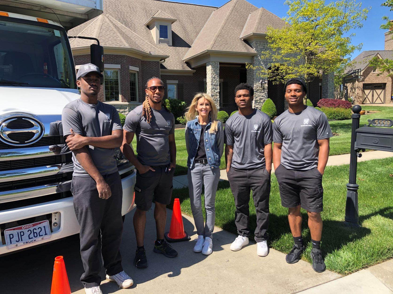 Four professional movers standing next to moving truck