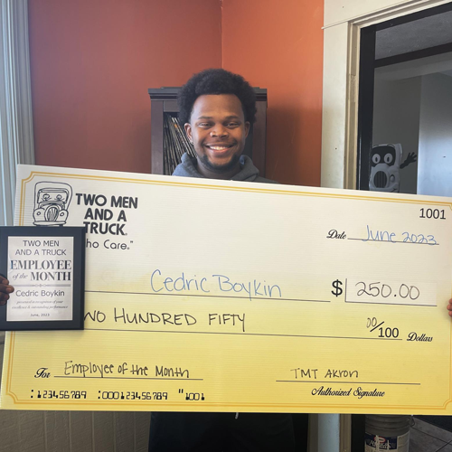 Cedric - Employee of the month holding a large check for winning the award
