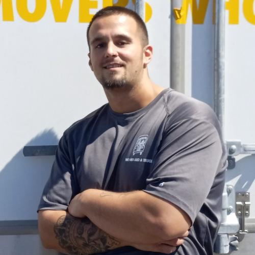 Mover, Charles, standing in front of a truck with his arms folded.