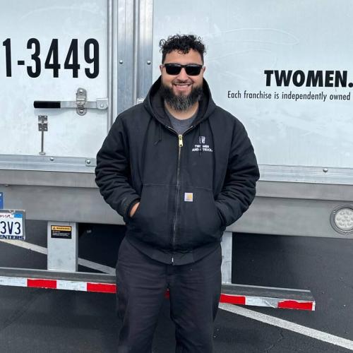 Smiling man stands behind the back of a truck