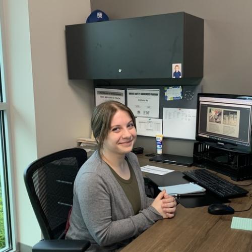 courtney is smiling sitting at a desk in front of a computer screen