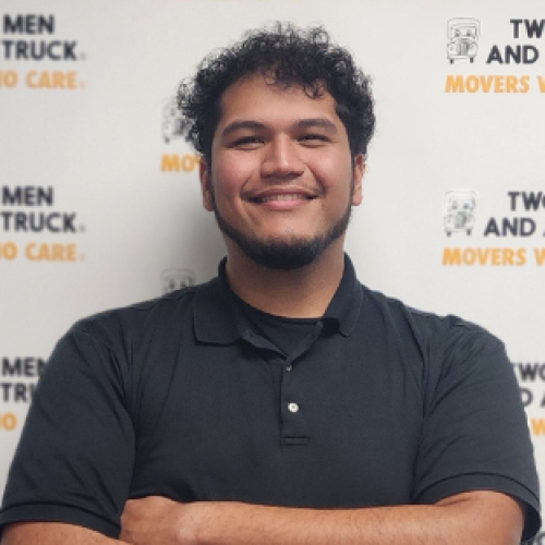 omar wearing a black polo standing in front of two men logo background