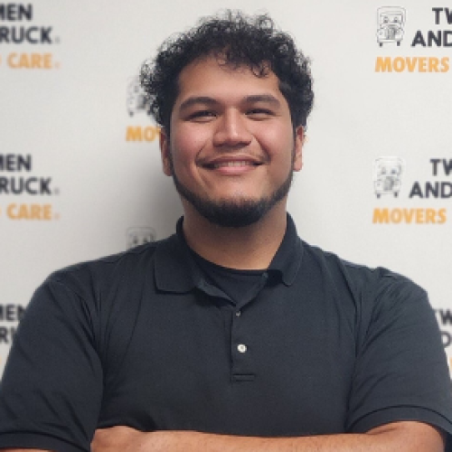 omar wearing a black polo standing in front of two men logo background