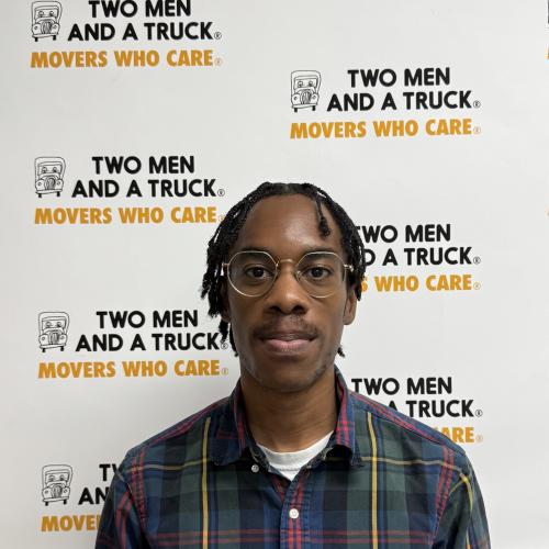 jalyn smoot standing in front of two men and a truck background wearing plaid green shirt and glasses