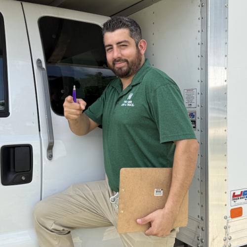 Two Men And A Truck move manager in Austin posing in front of moving truck.