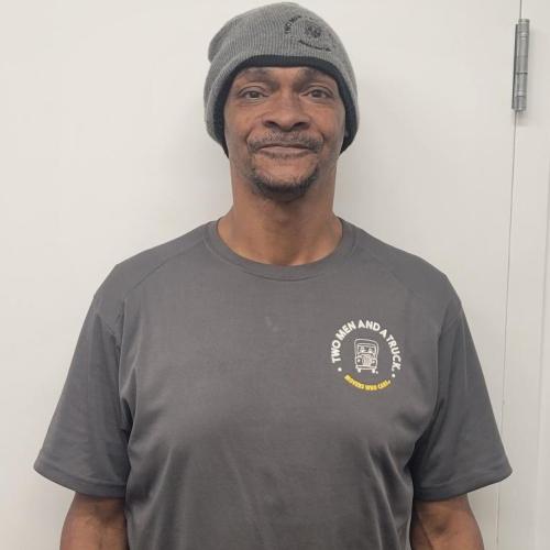 man smiling wearing a two men and a truck beanie and tshirt