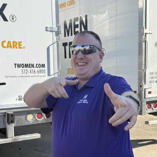 Moving company manager posing in front of moving truck doing the finger point. 