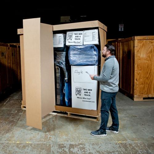 a manager looking over a cardboard crate with items inside