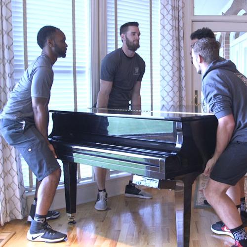 Four movers lifting a piano