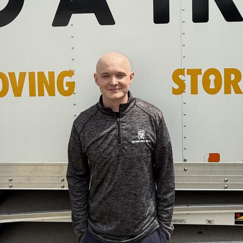 Customer service representative standing in front of a moving truck. 
