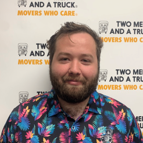 jordan standing in front of two men and a truck logo background wearing floral polo