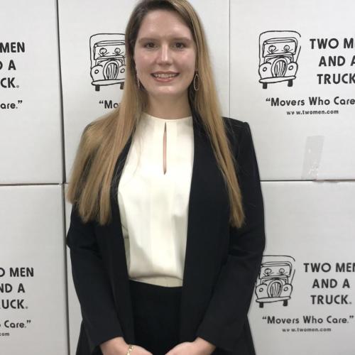 elizabeth wearing white and black shirt and standing in front of two men and a truck moving boxes