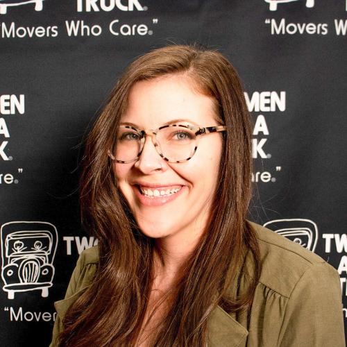 kirsten wearing a green shirt smiling and standing in front of two men and a truck backdrop