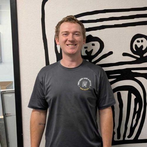 Zach - mover with two men and a truck standing in front of a wall with the company logo on it