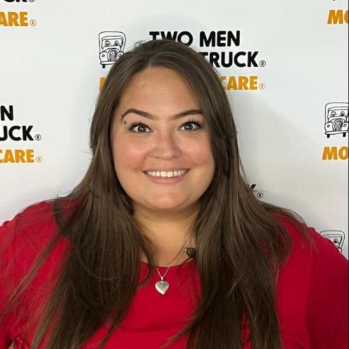 kayla wearing red shirt smiling and standing in front of two men and a truck backdrop