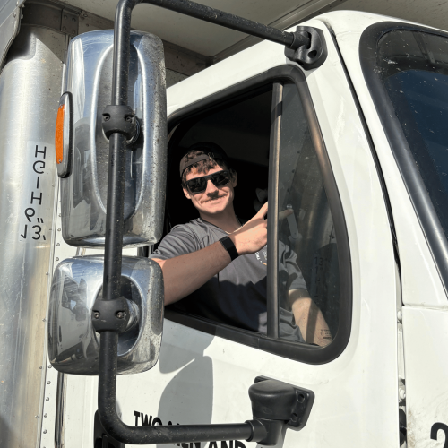 Xavier sitting in the moving truck posing for a picture.