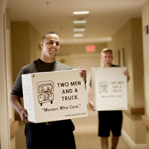 movers carrying boxes in an apartment hallway