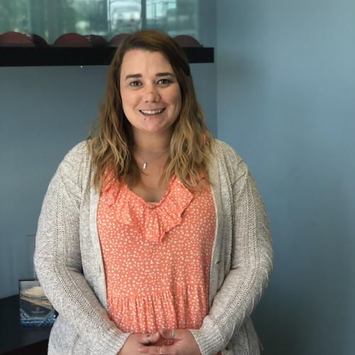 Casey standing in the office with her fingers crossed