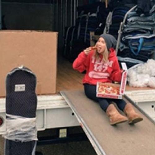 Kaitlin sitting on truck ramp eating pizza