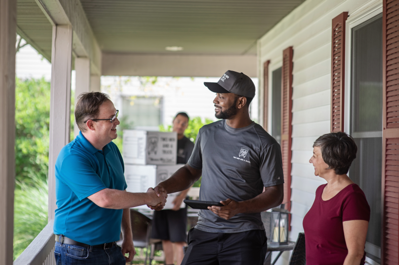 Mover shaking hands with customers on home porch