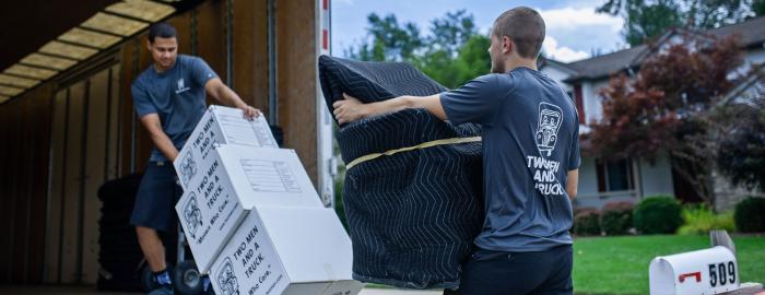 Movers loading a truck with heavy objects and boxes