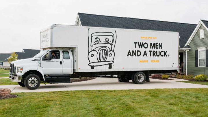 A moving truck parked in a driveway of a house