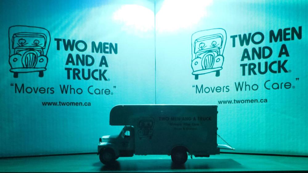 Movers putting Toys for Tots boxes into TWO MEN AND A TRUCK truck